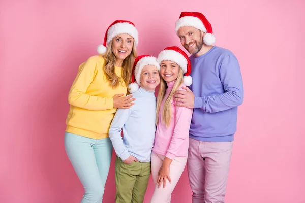 Foto van droom familie mama papa twee kleine kinderen dragen x-mas santa claus cap geïsoleerd op pastel roze kleur achtergrond — Stockfoto