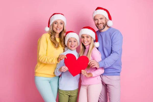 Φωτογραφία των Χ-μας χειμώνα Δεκέμβριος άνθρωποι μαμά μπαμπάς δύο μικρά παιδιά κατέχουν κάρτα καρδιά χαρτί φορούν σκούφο Σάντα Claus απομονωμένο ροζ χρώμα φόντο — Φωτογραφία Αρχείου