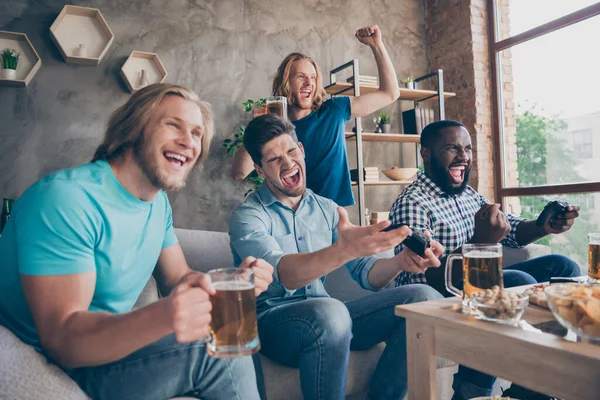 Retrato de cuatro simpáticos chicos alegres alegres alegres agradables jugando concurso de batalla deportiva de videojuegos que se divierten pasando el fin de semana en el apartamento de casa interior de estilo loft industrial en interiores — Foto de Stock