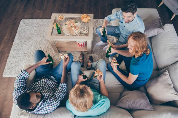 Top nad vysokým úhlem plné tělo fotografie pozitivní čtyři muži kamarádi mají univerzitní dovolená karanténa jíst pizza drink láhev pivo mluvit sedět divan v domě uvnitř — Stock fotografie