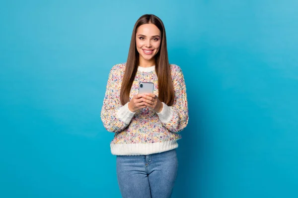 Foto der schönen attraktiven Dame lange gerade Frisur halten Telefon Hände online freiberufliche Arbeit Quarantäne lesen Nachrichten tragen lässig Pullover Jeans isoliert blaue Farbe Hintergrund — Stockfoto