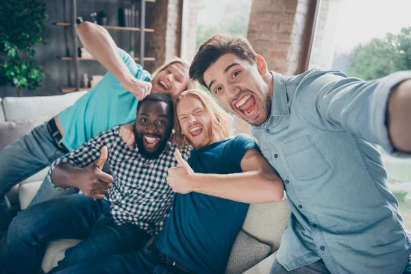 Retrato de positivo quatro homens companheiros desfrutar alegrar despedida de solteiro festa reunião aprovar tudo bem mostrar polegar para cima sinal fazer selfie sentar sofá conforto em casa dentro de casa — Fotografia de Stock