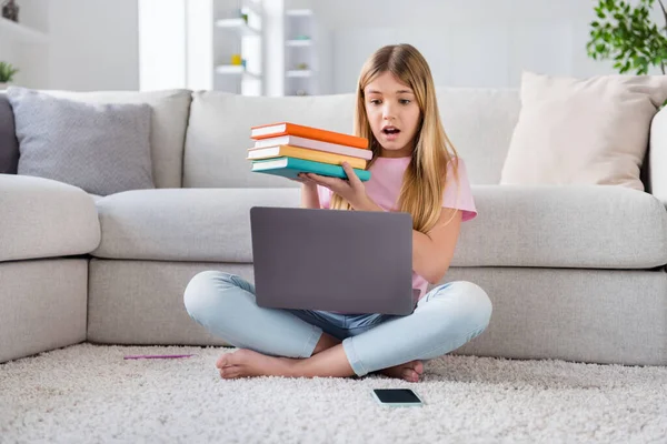 What i need read all books. Frustrated little kid girl sit floor study remote have laptop online tutor communication impressed exam task knowledge materials in house indoors — Stock Photo, Image