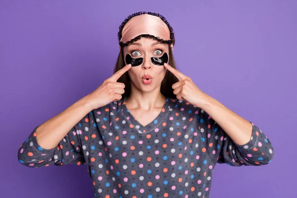 Foto di ragazza stupita punto indice dito viso occhio borse impressionato sano effetto sonno indossare punteggiato maschera pigiama isolato su sfondo di colore viola — Foto Stock