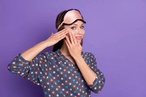 Photo of cheerful girl apply eye patch before recreation weekend healthy soft sleep wear eye mask dotted sleepwear isolated over violet purple color background