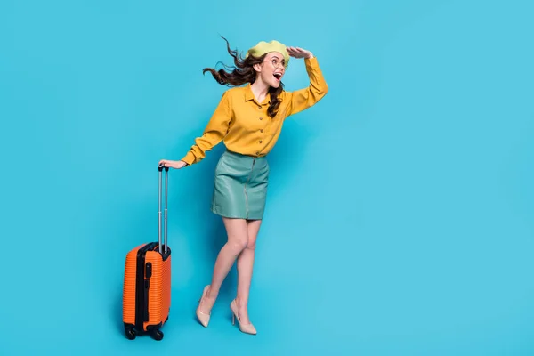 全长照片兴奋的女游客牵着手看飞机波浪般的发型飞扬着行李穿着黄色衬衫风格时髦时髦的高跟鞋与蓝色背景隔离 — 图库照片