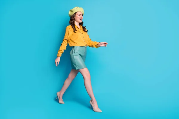 Full size profile side photo of attractive sweet lady go walk copyspace enjoy rest relax wear good look clothes headwear isolated over blue color background — стоковое фото