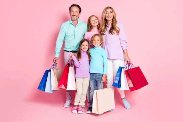 Pleine longueur photo de personnes de la famille profiter du shopping papa papa maman maman trois petits enfants tenir des sacs isolés sur fond de couleur pastel — Photo