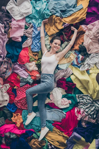 Alto ángulo por encima de la vista vertical foto de alegre señora divertida limpieza de primavera hogar acostado muchas cosas de ropa pila piso shopper rodeado de ventas no les importa desorden extender las manos en el interior —  Fotos de Stock