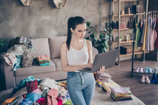Портрет серйозної дівчини використовує пошук ноутбуків Інтернет-магазин хоче купити нову колекцію поза продажем одяг джинсові джинси в будинку в приміщенні — стокове фото
