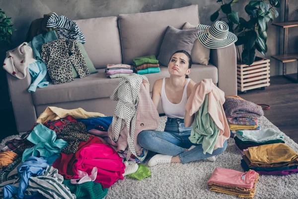 Top above high angle view photo of frustrated girl prepare for boyfriend date hold sweater shirt have problem what wear sigh sit floor carpet legs crossed folded in house indoors — Stock Photo, Image