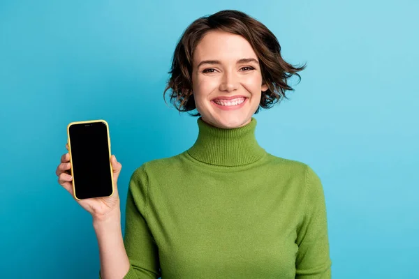 Porträt positiver Mädchen Promoter halten Smartphone-Display neue Gerät Produkt tragen gut aussehenden Pullover isoliert über blauem Hintergrund — Stockfoto