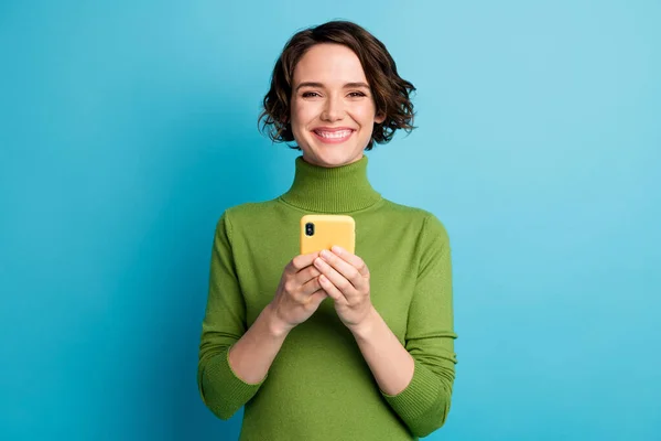 Retrato de niña alegre positivo uso smartphone disfrutar de la comunicación en red social desgaste verde estilo elegante suéter de moda aislado sobre fondo de color azul —  Fotos de Stock