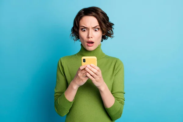 信じられない。驚きの女の子のブロガーは、携帯電話を使用して感銘を受けた恐ろしい投稿コメントを着用スタイルスタイリッシュなトレンディーなセーター青の色の背景に隔離 — ストック写真