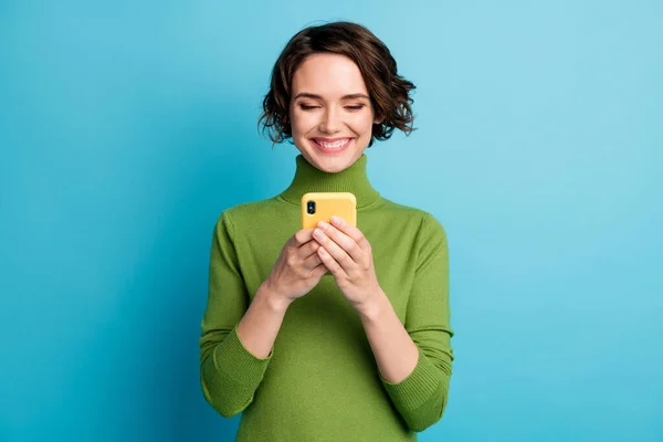 Portret van positieve vrolijke blogger meisje gebruik maken van mobiele telefoon lees social media nieuws communicatie slijtage stijl stijlvolle trendy pullover geïsoleerd over blauwe kleur achtergrond — Stockfoto