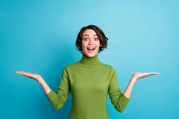 Portré megdöbbent lány promoter bizonyítani hihetetlen hirdetések promóció tartsa kezét lenyűgözött kopás zöld jumper elszigetelt kék háttér — Stock Fotó
