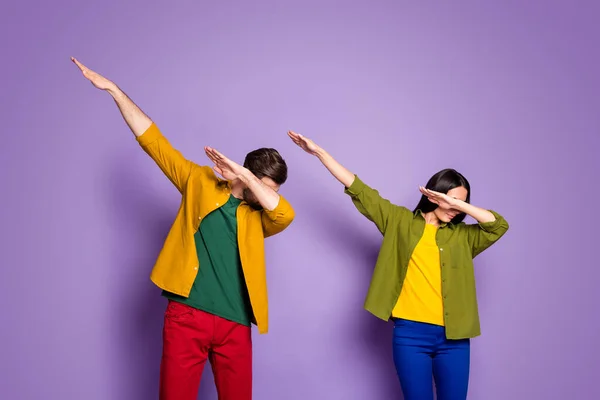 Foto señora fresco chico estudiantes pareja bailando moderno extraño juventud movimientos dab paso sincronía movimiento desgaste casual verde amarillo camisas pantalones aislado púrpura color fondo — Foto de Stock