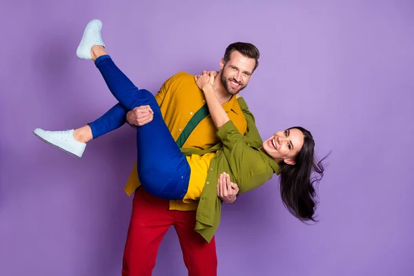 Foto charmante dame knappe verloofde man paar dragen vrouw bruid armen speelse trouwdag swinging niet bang dragen casual heldere shirts broek outfit geïsoleerde paarse kleur achtergrond — Stockfoto