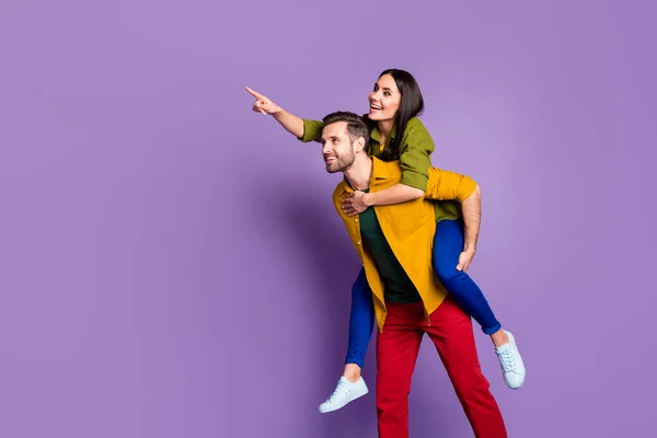 相貌漂亮的女士帅哥夫妇背着背手感不错的心情显示国外著名建筑游客穿着休闲衫裤子孤立的紫色背景 — 图库照片