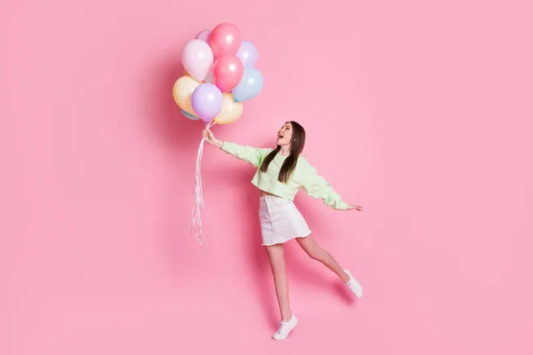 Full body foto van verbaasd geschokt gek vrolijk meisje houden veel luchtballonnen vliegen lucht onder de indruk genieten vreugde dragen wit trui sneakers geïsoleerde pastel kleur achtergrond — Stockfoto