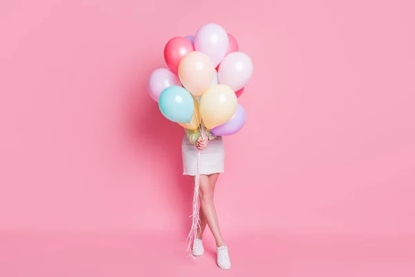 Full Size Foto von lustigen Dame kommen Geburtstagsparty halten viele Luftballons versteckt Gesicht Überraschung Besuch tragen lässige grüne Crop Pullover Jeans Rock Schuhe isoliert rosa Pastellfarbe Hintergrund — Stockfoto