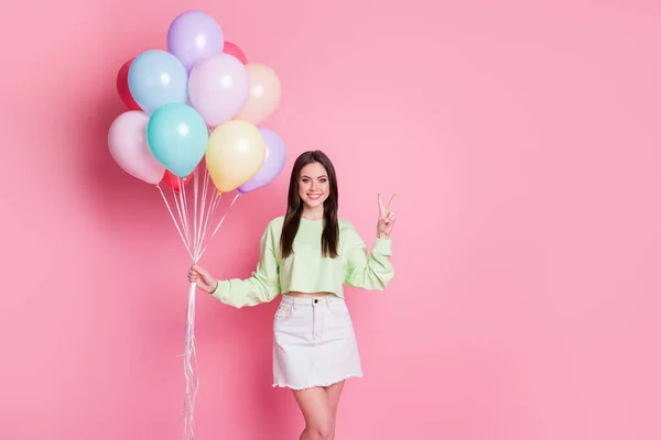 Photo of attractive funny lady birthday party best friend guest bring carry many air balloons surprise wear casual green crop pullover jeans mini skirt isolated pink pastel color background