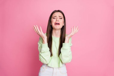 Photo of depressed lady long hairdo disappointed crying desperate raise arms unfair life grief bad terrible faith wear casual green cropped sweatshirt pullover isolated pink color background clipart