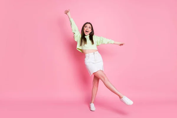 Foto de comprimento total de atraente jovem senhora levantar braços perna alta dança estudantes festa bom humor desgaste casual pulôver barriga nua jeans saia sapatos isolado cor rosa fundo — Fotografia de Stock