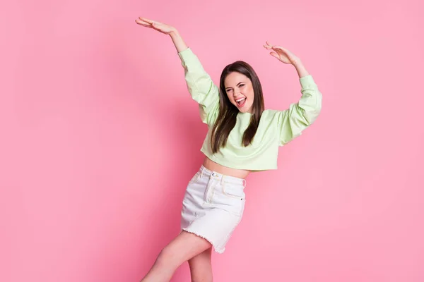 Photo of attractive funky youngster millennial lady raise arms dancing students party slim figure wear casual green crop pullover naked belly jeans spódnica odizolowany różowy kolor tła — Zdjęcie stockowe