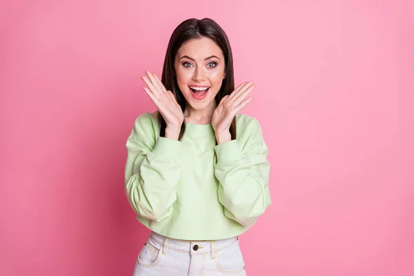 Foto van aantrekkelijke grappige geschokte dame lang kapsel open mond verbaasd armen in de buurt van wangen dragen casual bijgesneden groene trui trui trui geïsoleerde roze pastel kleur achtergrond — Stockfoto