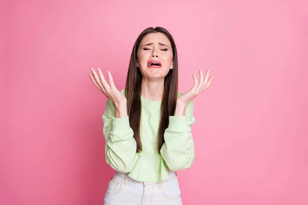 Фото депрессивной леди длинные волосы разочарованы плакать отчаянно поднять руки несправедливой жизни горе ужасная вера носить случайные зеленые обрезанные свитер свитер пуловер изолированный розовый цвет фона — стоковое фото