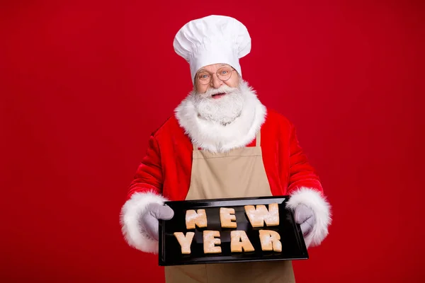 Elegante pelo gris blanco barbudo santa claus hornear hoja jengibre romper galletas x-mas carta usar gorra delantal agarradera aislado rojo brillante brillo color fondo —  Fotos de Stock