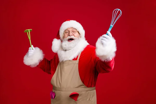 Photo of crazy modern Santa Claus hold naczynia kuchenne x-mas obiad gotowanie nosić czerwony kostium fartuch odizolowany na jasny połysk kolor tła — Zdjęcie stockowe