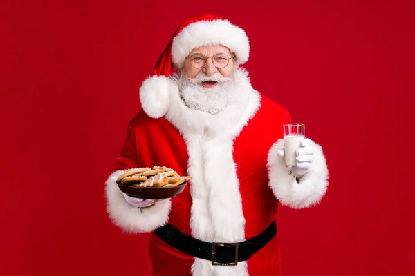 Zdjęcie szalony funky Santa Claus trzymać X-mas tradycji imbir chleb ciasteczka płyta mleko szkło nosić czerwony kostium nakrycia głowy izolowane na jasny połysk kolor tła — Zdjęcie stockowe
