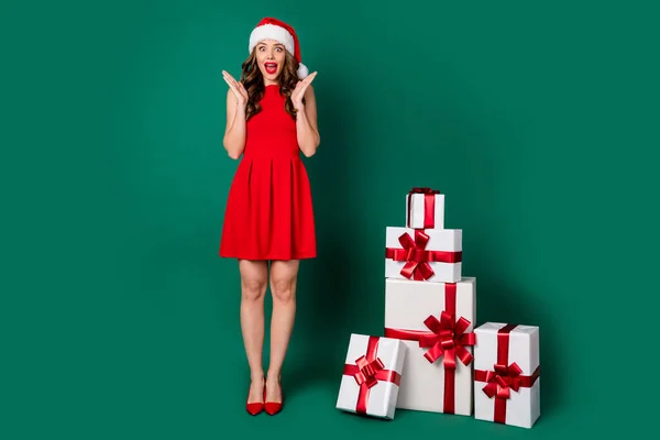 Full size photo of shocked girl in santa claus headwear cap impressed fairy magic miracle newyear gift box delivery wear skirt legs high-heels isolated over green color background
