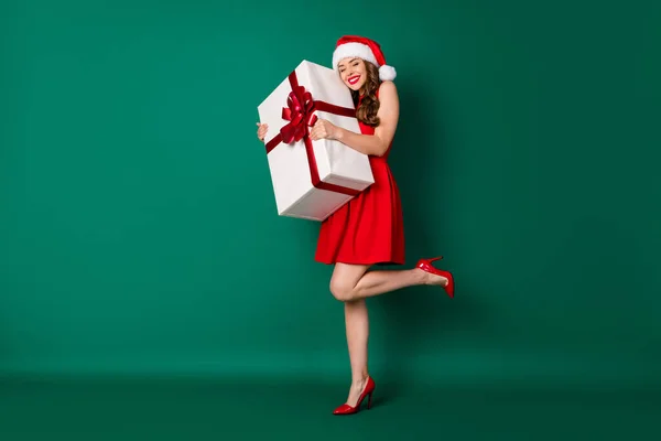 Δεν το πιστεύω αυτό. Πλήρες μέγεθος φωτογραφία χαριτωμένο γλυκό κορίτσι σε Santa Claus κεφαλόδεσμο αγκαλιά αγκαλιάσει απολαύσετε μεγάλο θαύμα x-mas μαγικό giftbox φορούν πόδια φούστα ψηλά τακούνια απομονωμένο πράσινο χρώμα φόντο — Φωτογραφία Αρχείου