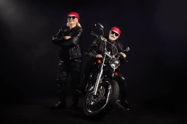 Full body foto di vecchi motociclisti uomo signora coppia azionamento chopper viaggio sentire giovane rock moto festival braccia incrociate usura rocker pelle vestito sunglass bandana isolato colore nero sfondo — Foto Stock