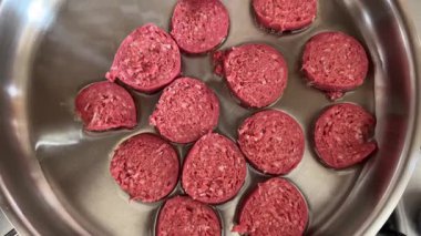 Raw slices of Turkish sucuk sausage cooking in sunflower oil pan