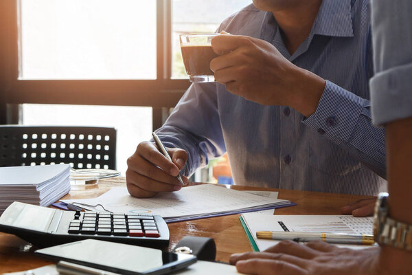 Business team meeting and discussing project plan. Businessman holding a cup of coffee and working on his project with his colleagues in meeting room. Professional investor working with business project together. Finance managers task