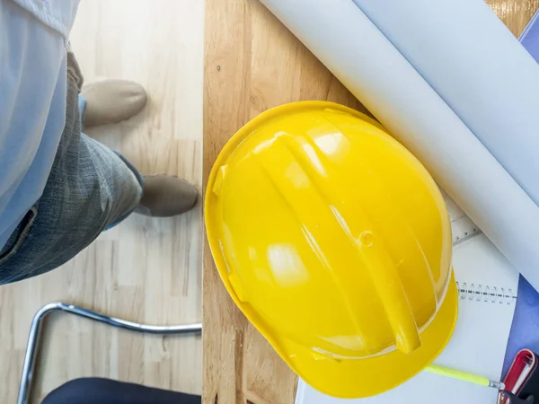 Helmet and blueprint on desk with architect, top view