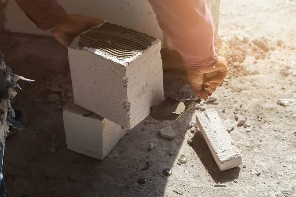 Bricklayer plastering cement on brick. Mason worker building exterior walls.