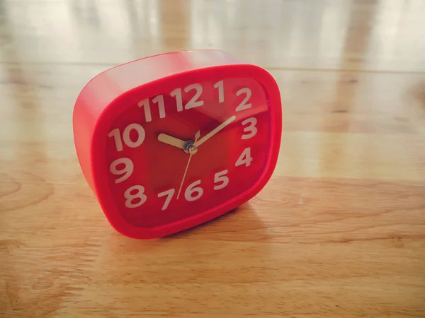 Red rectangle alarm clock on wooden table