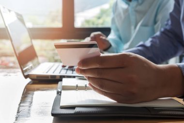 İşadamı kredi kartı tutuyor ve dizüstü bilgisayar kullanıyor. Online alışveriş yaparken ödeme yapma. E-ticaret ve modern teknoloji konsepti