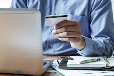 İşadamı kredi kartı tutuyor ve dizüstü bilgisayar kullanıyor. Online alışveriş yaparken ödeme yapma. E-ticaret ve modern teknoloji konsepti