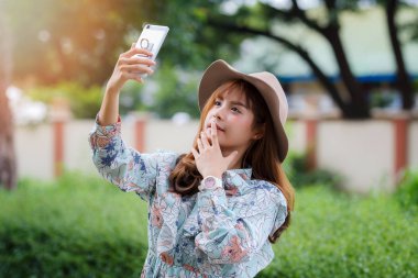 Vintage elbiseli Pretty asyalı kız parkta selfie çekerken.