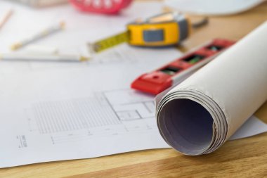 Ahşap masa üzerinde plan ve ölçüm aleti