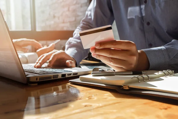İşadamı kredi kartı tutuyor ve dizüstü bilgisayar kullanıyor. Online alışveriş yaparken ödeme yapma. E-ticaret ve modern teknoloji konsepti