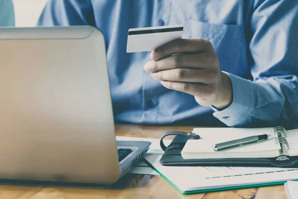 İşadamı kredi kartı tutuyor ve dizüstü bilgisayar kullanıyor. Online alışveriş yaparken ödeme yapma. E-ticaret ve modern teknoloji konsepti