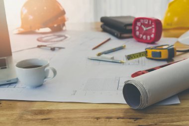 Bina planı, ölçüm aleti ve tahta masanın üzerinde bir fincan kahve.