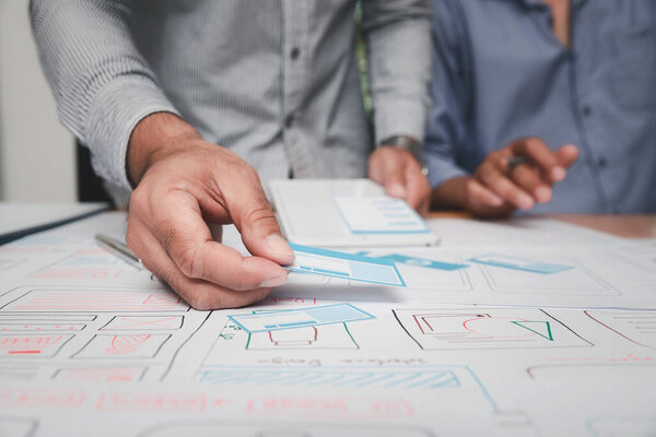 Дизайнеры UX или пользовательского интерфейса разрабатывают прототип приложения для смартфонов.